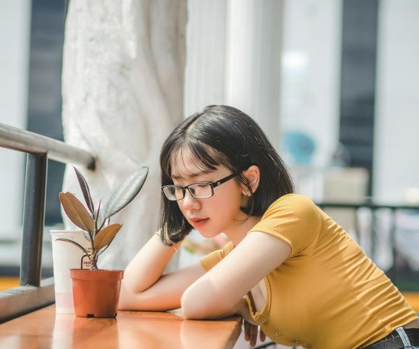 A young girl sitting cross-legged with eyes closed, looking calm and focused in a peaceful setting.